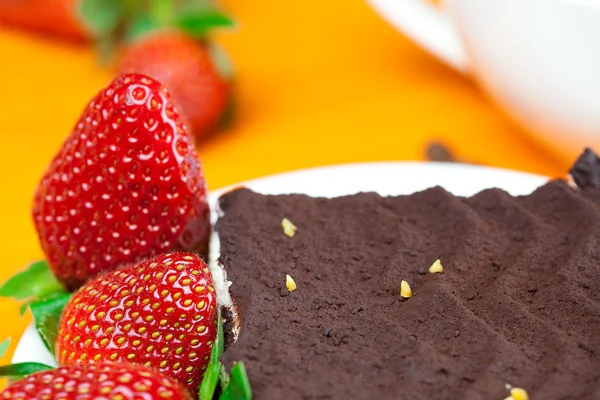 Cake on a plate and strawberries lying on the orange fabric — Stock Photo, Image