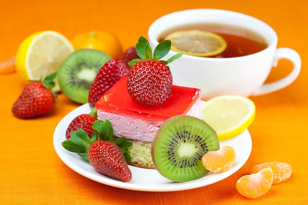 Citronte, kiwi, tårta och jordgubbar liggande på orange tyg — Stockfoto