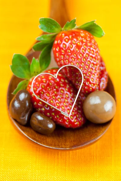 Jordbær, hjerter og chokolade slik i træ ske af th - Stock-foto