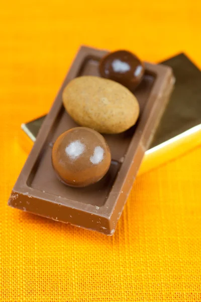 Čokoládové tyčinky a candy na oranžové textilie — Stock fotografie
