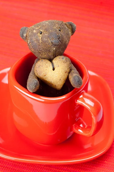 Плюшевий ведмедик ручної роботи і печиво у вигляді серця в чашці — стокове фото