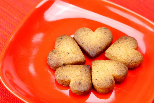 Печенье в форме сердца в пластине на красном фоне — стоковое фото