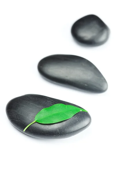 Pedras de spa preto com folha verde e uma gota de água isolada — Fotografia de Stock
