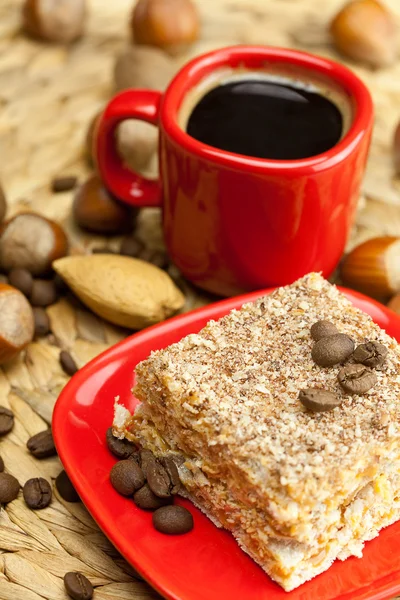 Торт на тарелке, орехи и чашку кофе на плетеном коврике — стоковое фото