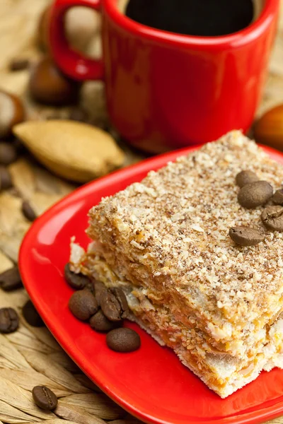 Cake on a plate, nuts and a cup of coffee on a wicker mat — Stock Photo, Image