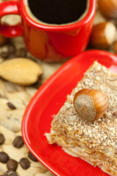 Kage på en tallerken, nødder og en kop kaffe på en fletmåtte - Stock-foto