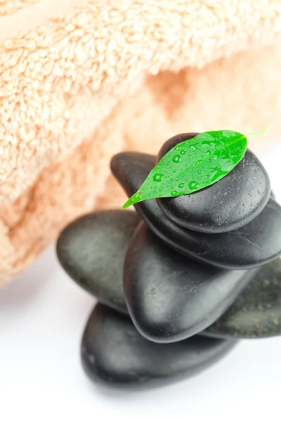 Black spa stones with green leaf and a drop of water on the tow — Stock Photo, Image