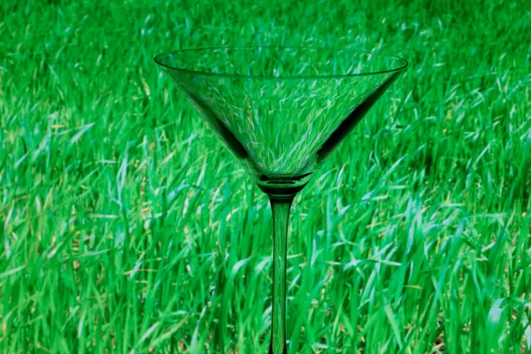 Konzeptionell beleuchtetes Martini-Glas auf grünem Hintergrund — Stockfoto