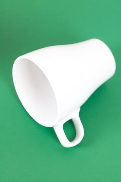 Taza blanca acostada sobre un fondo verde — Foto de Stock