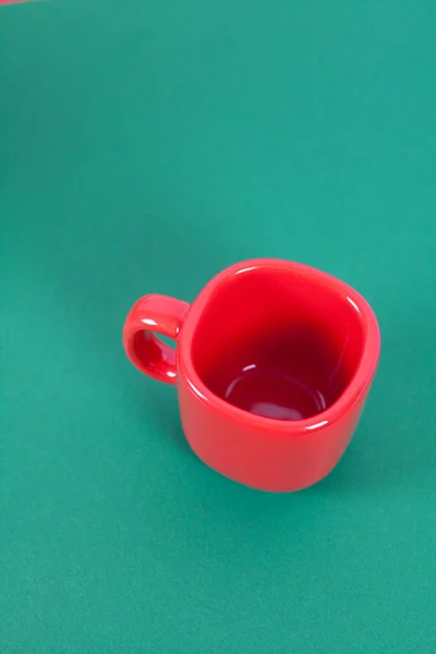 Красная чашка, лежащая на зеленом фоне — стоковое фото