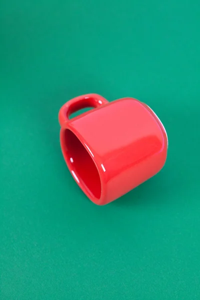 Taza roja acostada sobre un fondo verde — Foto de Stock