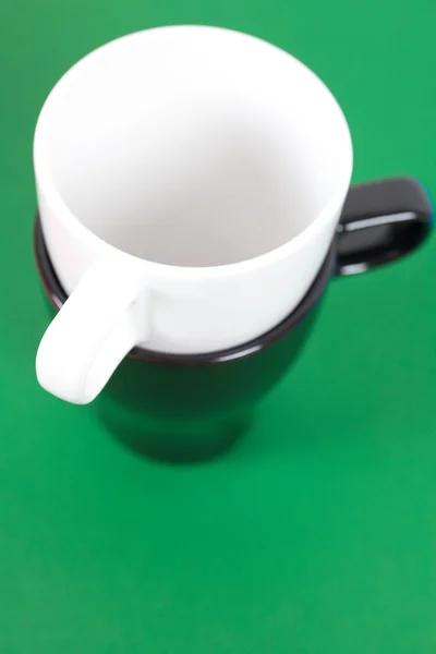 Tasse noire et blanche debout sur un fond vert — Photo