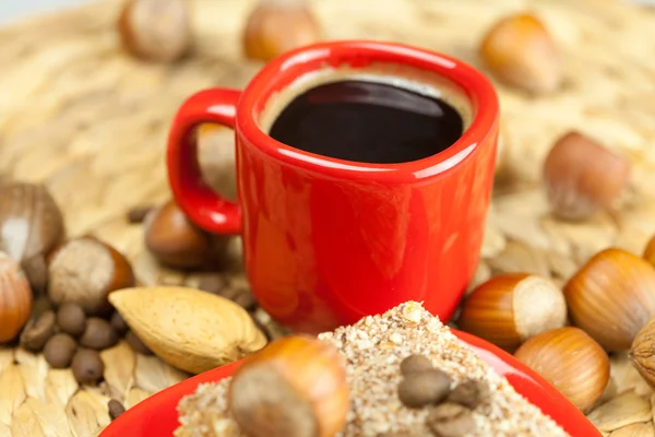 Cake on a plate, nuts and a cup of coffee on a wicker mat — Stock Photo, Image