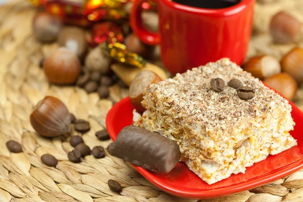 Cake on a plate, nuts and a cup of coffee on a wicker mat — Stock Photo, Image