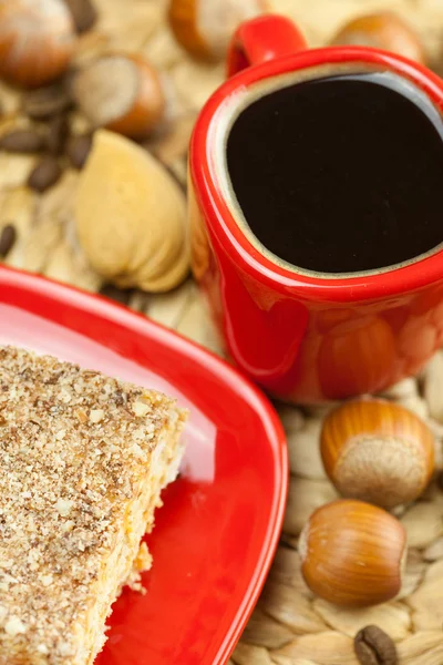 Pastel en un plato, nueces y una taza de café en una estera de mimbre —  Fotos de Stock