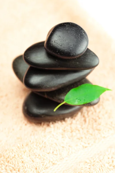 Piedras de spa negras con hoja verde y una gota de agua en el remolque —  Fotos de Stock