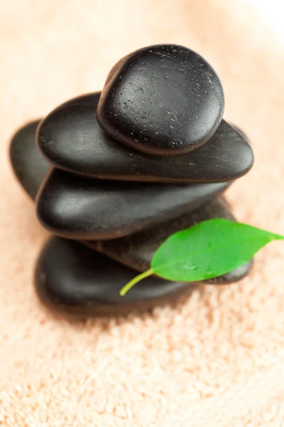 Pedras de spa pretas com folha verde e uma gota de água no reboque — Fotografia de Stock