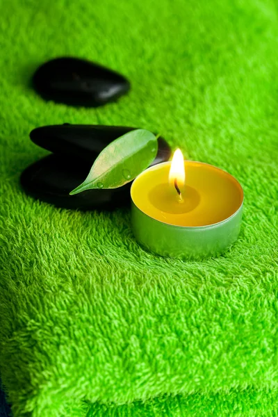Queimando velas e pedras pretas spa deitado sobre a toalha — Fotografia de Stock