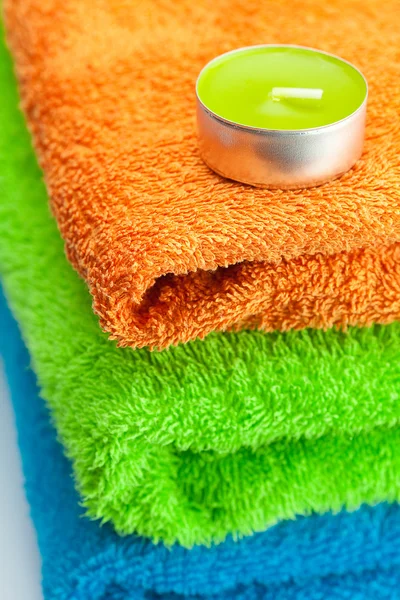 Achtergrond van de drie multi gekleurde terry handdoeken en kaars — Stockfoto