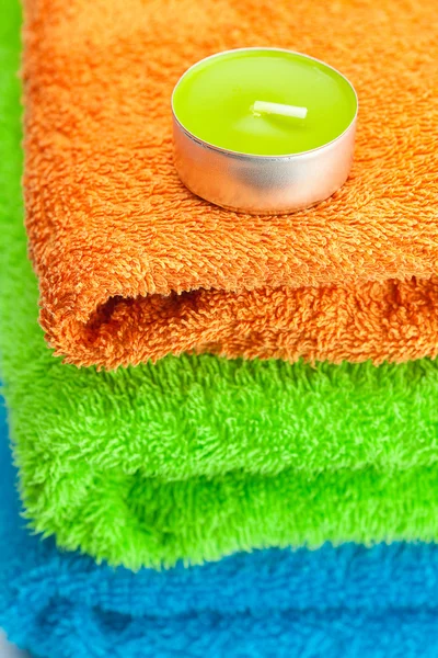 Achtergrond van de drie multi gekleurde terry handdoeken en kaars — Stockfoto