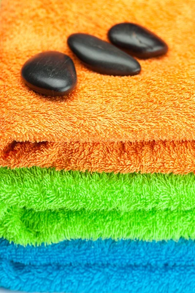 Üç adet çok renkli terry havlu ve spa siyah arka plan — Stok fotoğraf