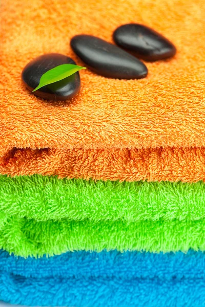 Achtergrond van de drie multi-gekleurde terry handdoeken en spa zwart — Stockfoto