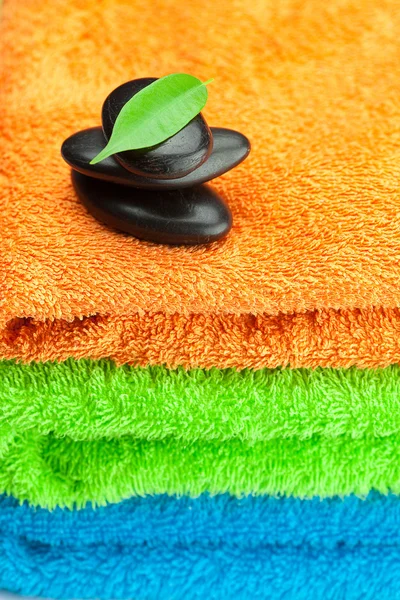 Sfondo dei tre spugna multicolore asciugamani e spa nero — Foto Stock