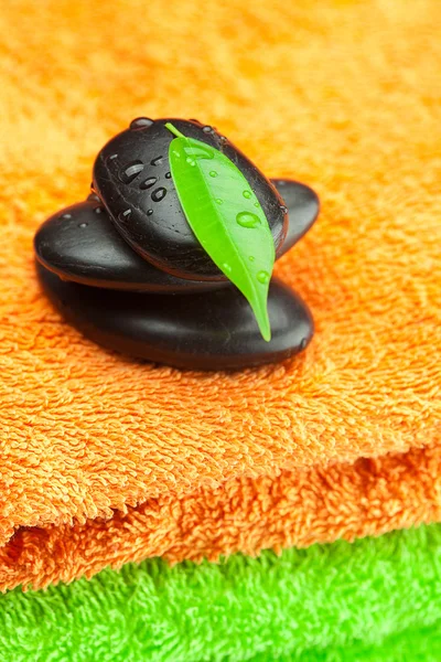 Bakgrunden till tre flerfärgade frotté handdukar och spa svart — Stockfoto