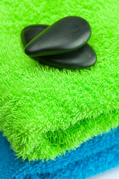 Auf dem Handtuch liegende schwarze Wellness-Steine — Stockfoto