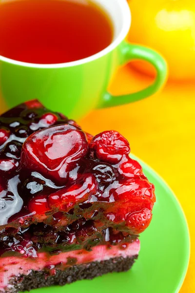 Hermoso pastel con bayas en un plato y una taza de té en el o — Foto de Stock