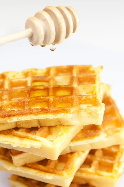 Delicious Belgian waffles and stick to honey isolated on white — Stock Photo, Image