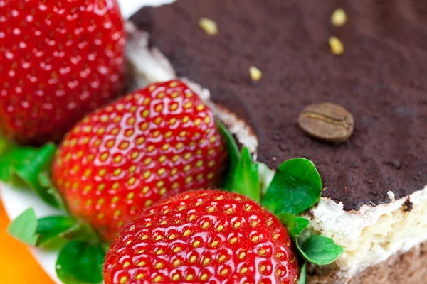 Cake on a plate and strawberries lying on the orange fabric Stock Image