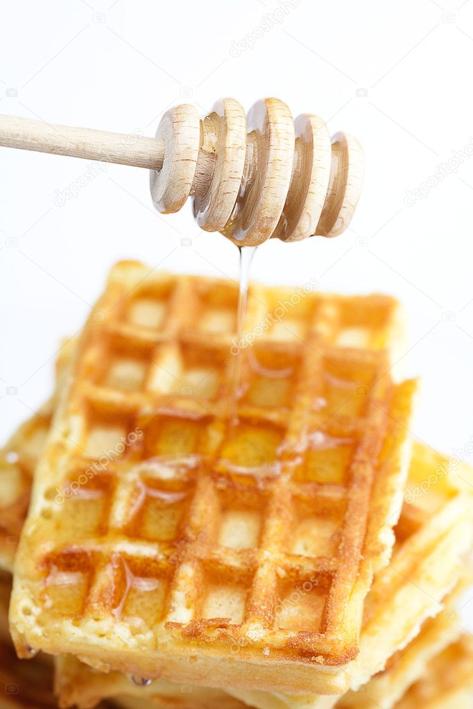 Delicious Belgian waffles and stick to honey isolated on white