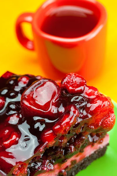 Beautiful cake with berries on a plate and a cup of tea on the o — Stock Photo, Image