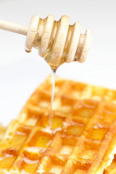 Delicious Belgian waffles and stick to honey isolated on white — Stock Photo, Image