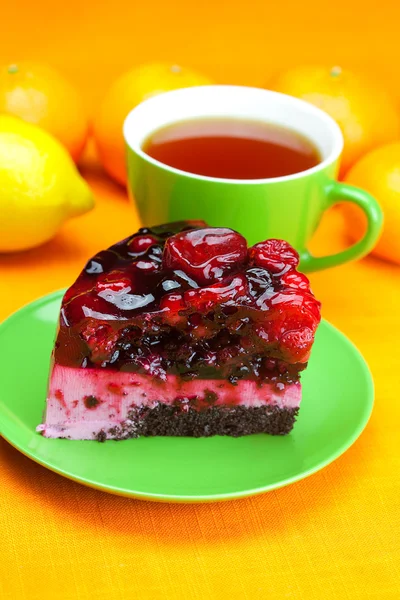Beautiful cake with berries on a plate and a cup of tea on the o — Stock Photo, Image