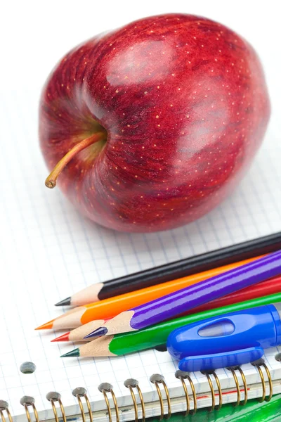 Яблоко, блокноты и карандаши изолированы на белом — стоковое фото