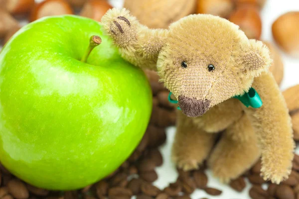 Ursinho de pelúcia com um arco, maçã, grãos de café e nozes — Fotografia de Stock