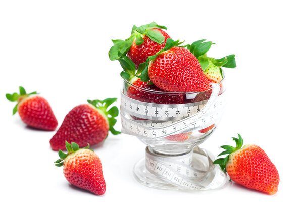 Big juicy red ripe strawberries in a glass bowl and measure tape