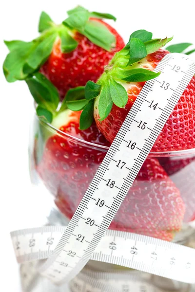 Big juicy red ripe strawberries in a glass bowl and measure tape — Stock Photo, Image