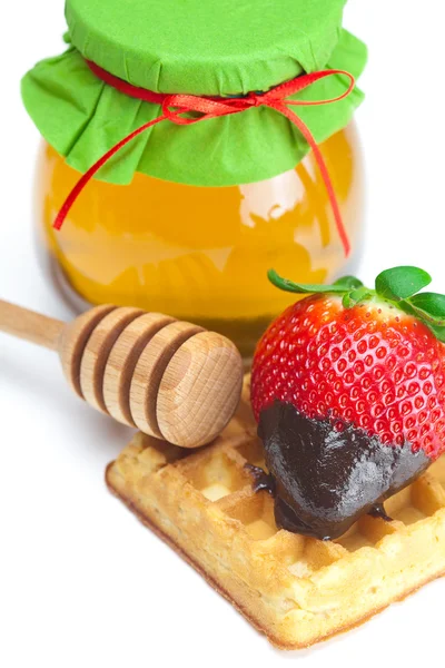 Velké šťavnaté zralé jahody v čokoládě, sklenice medu a waf — Stock fotografie