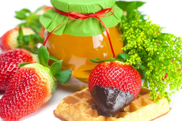 Große saftige reife Erdbeeren in Schokolade, ein Glas Honig und Waf — Stockfoto