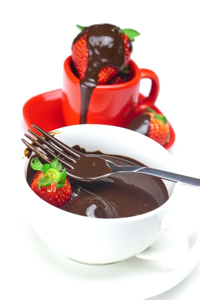 Melted chocolate in a cup, fork and strawberries isolated on whi