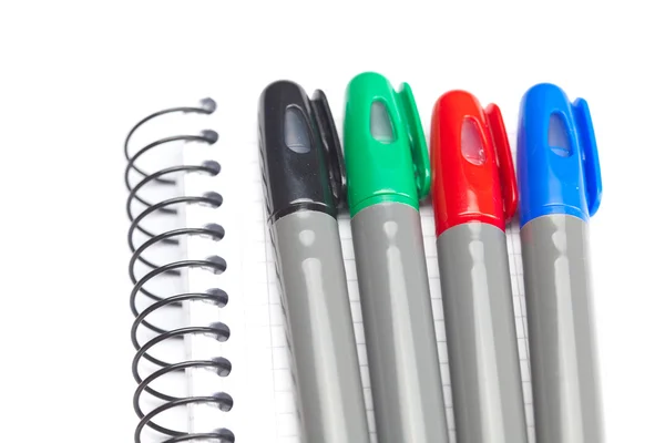 Marcadores coloridos e um caderno isolado em branco — Fotografia de Stock
