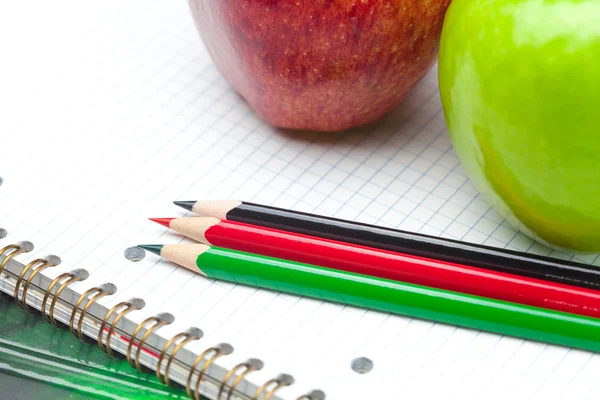 Яблоко, блокноты и карандаши изолированы на белом — стоковое фото