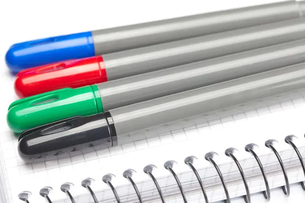 Marcadores coloridos e um caderno isolado em branco — Fotografia de Stock