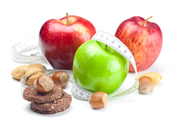 Яблоко, орехи, печенье и измерительная лента изолированы на белом — стоковое фото