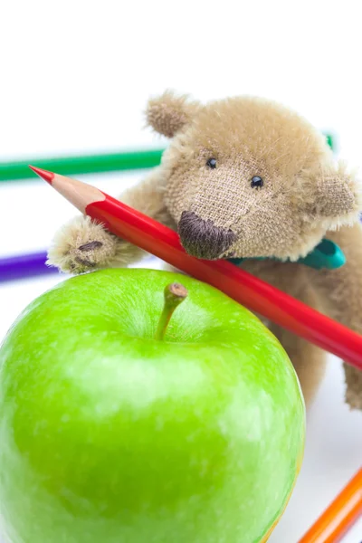 Плюшевый мишка, яблоко и цветные карандаши изолированы на белом — стоковое фото
