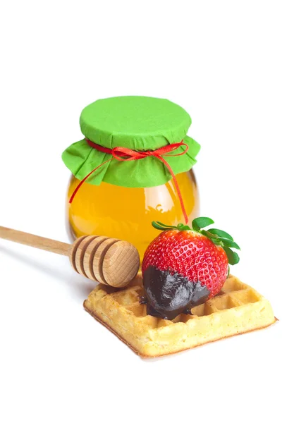 Grote sappige rijpe aardbeien in chocolade, een pot van honing en waf — Stockfoto