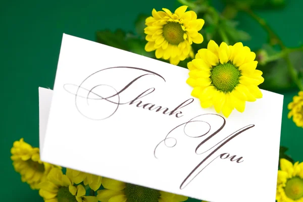 Žluté sedmikrásky a kartu podepsali Děkuji na zeleném pozadí — Stock fotografie
